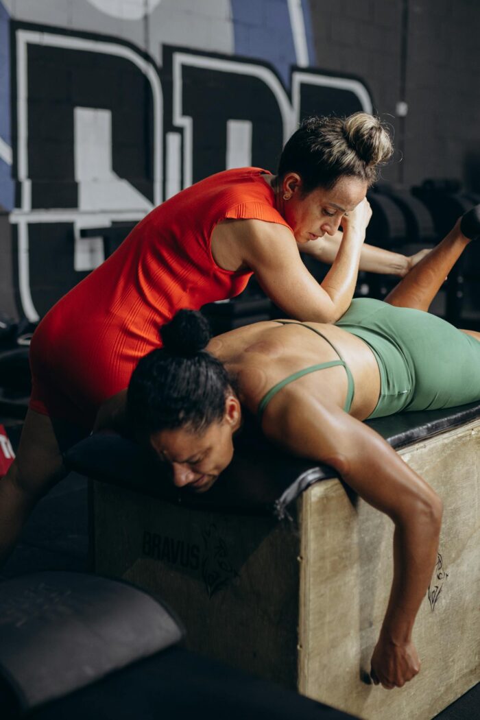 A woman doing a plank on a bench with another woman